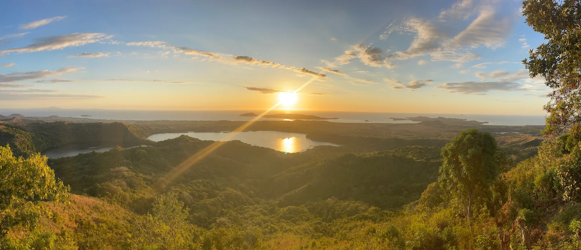 Sonsondergang oor heuwels en 'n meer op Madagaskar, vanuit die lug gesien